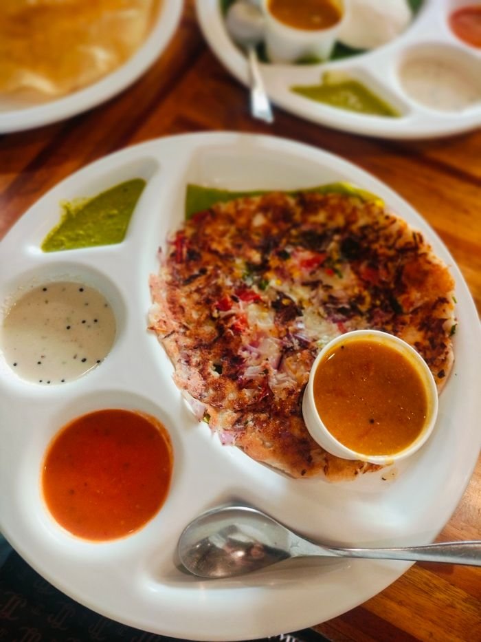 Delicious south Indian rawa uttapam served with coconut chatni and dips, captured in Delhi, India.