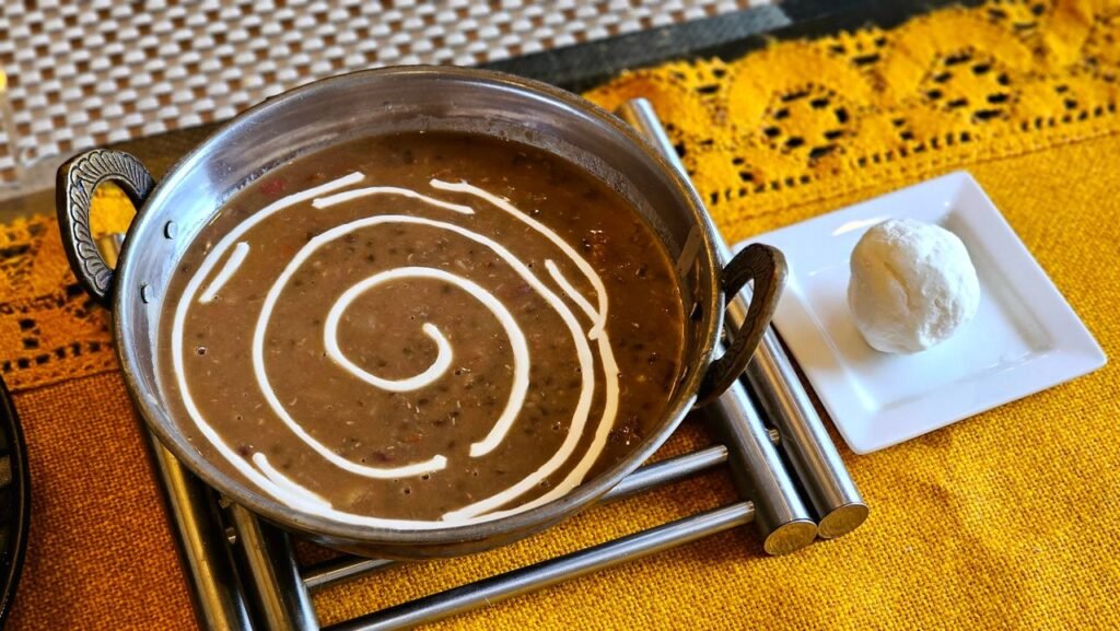 Close-up of dal makhani with a swirl of cream and butter on a vibrant yellow setting, perfect for culinary blogs.